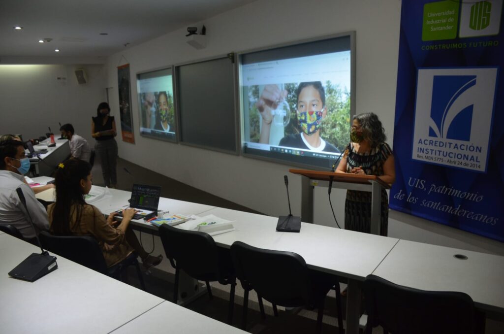 La imagen muestra a la profesora Andrea Hernández Quirama, directora de Investigación y Extensión de la Facultad de Ciencias Humanas, presenta ante el publico asistente el lanzamiento de la nueva fase de Investigadores por Naturaleza.  