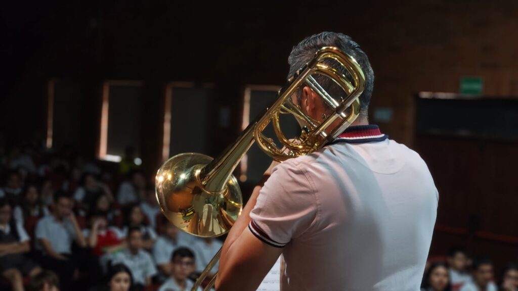 Imagen muestra a trombonista UIS ejecutando el instrumento frente al público estudiantil del Colegio de Santander