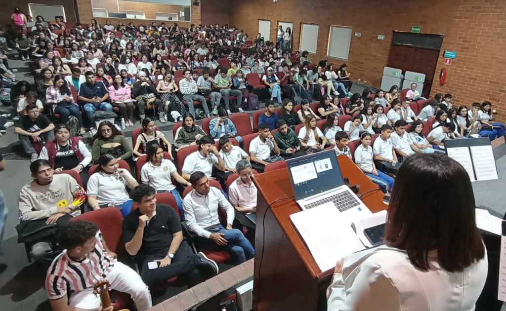 Momento de la conferencia que muestra la conferenciante y gran parte del público asistente.