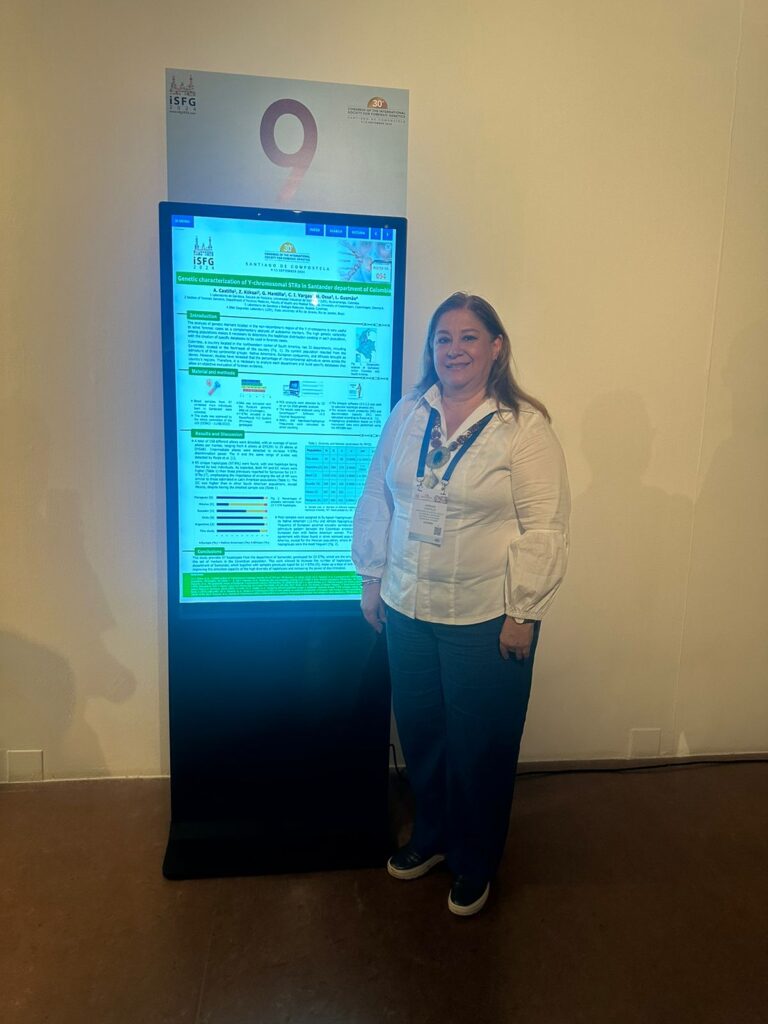 Profesora Adriana Castillo Pico junto al póster electrónico presentado en el Congreso de la Sociedad Internacional de Genética Forense 