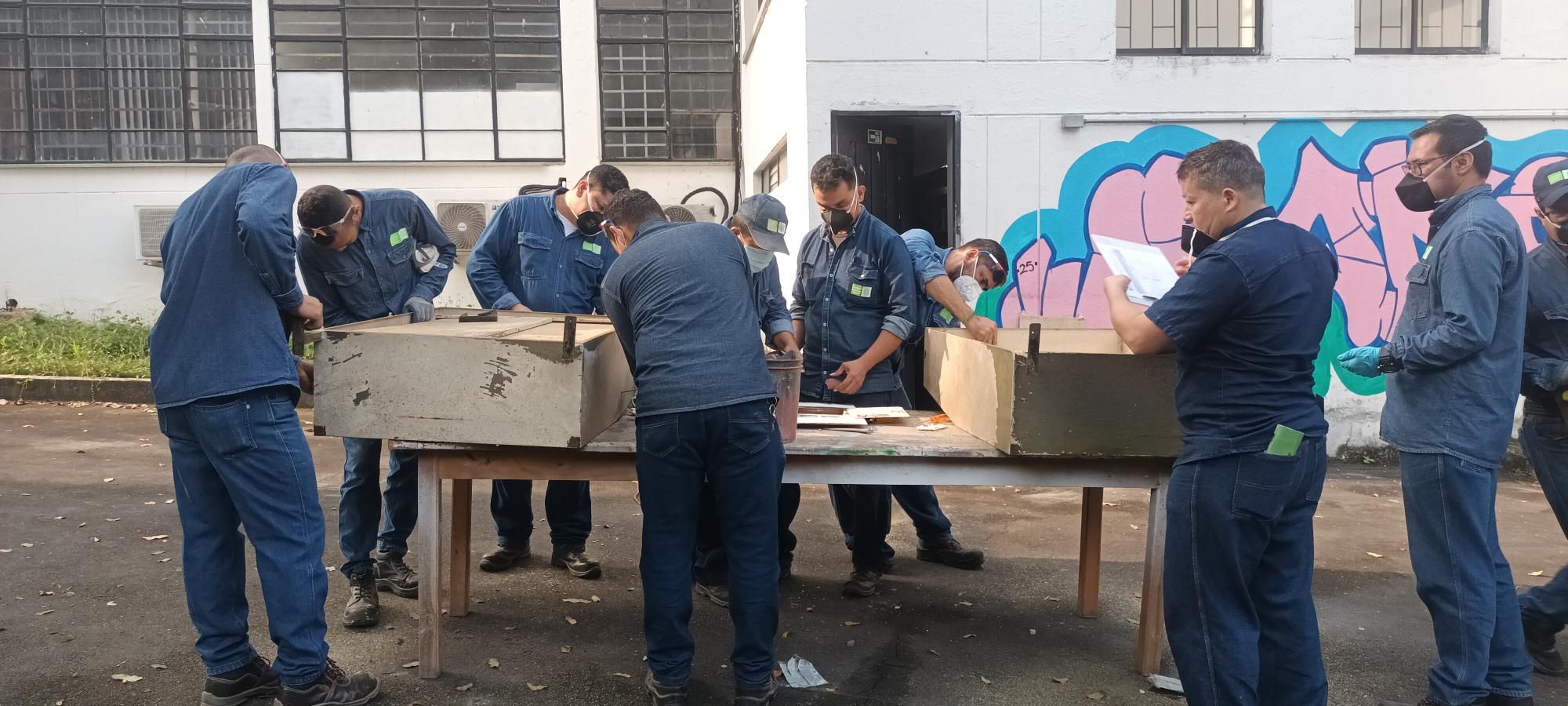 Funcionarios de planta física trabajando en curso de pintura.