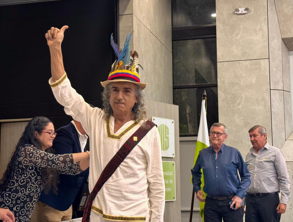 Egresado con sombrero adornado con plumas levanta el brazo en el acto conmemorativo en la UIS.