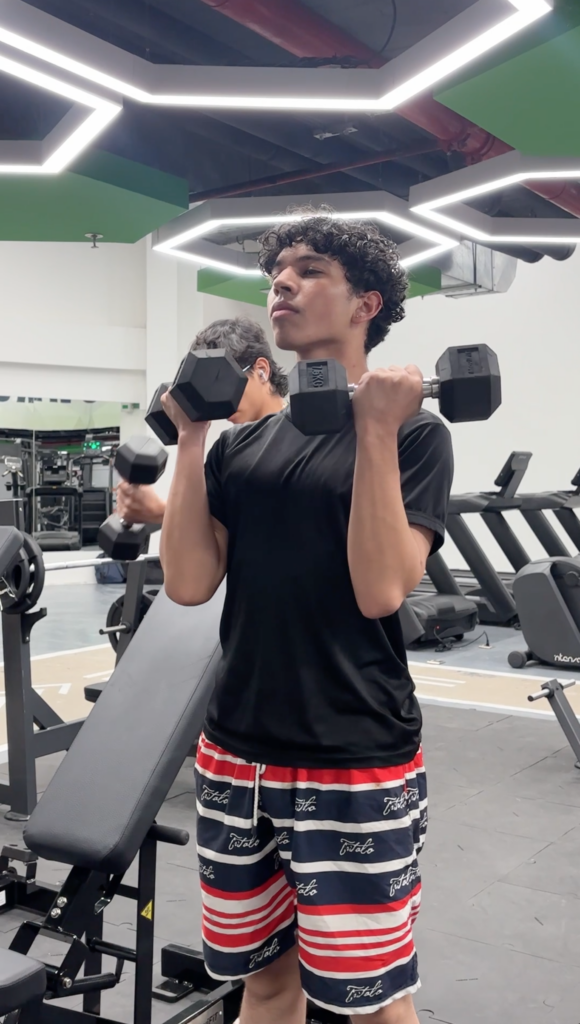 Joven levantando mancuernas en gimnasio