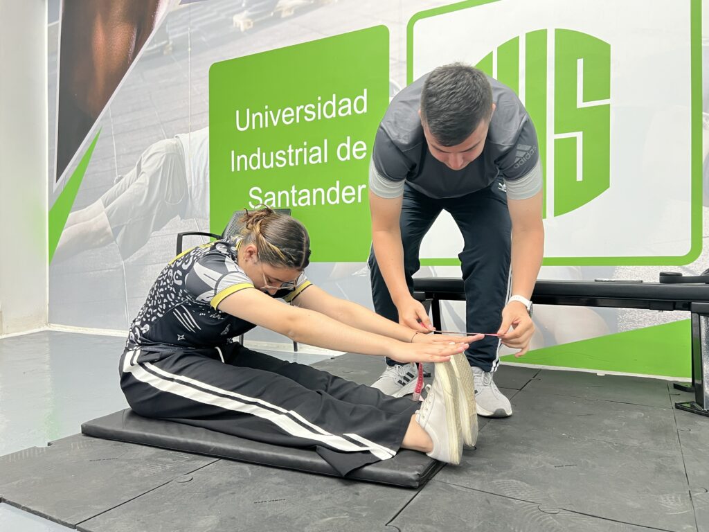 Mujer hace ejercicio en gimnasio con supervisión de instructor.