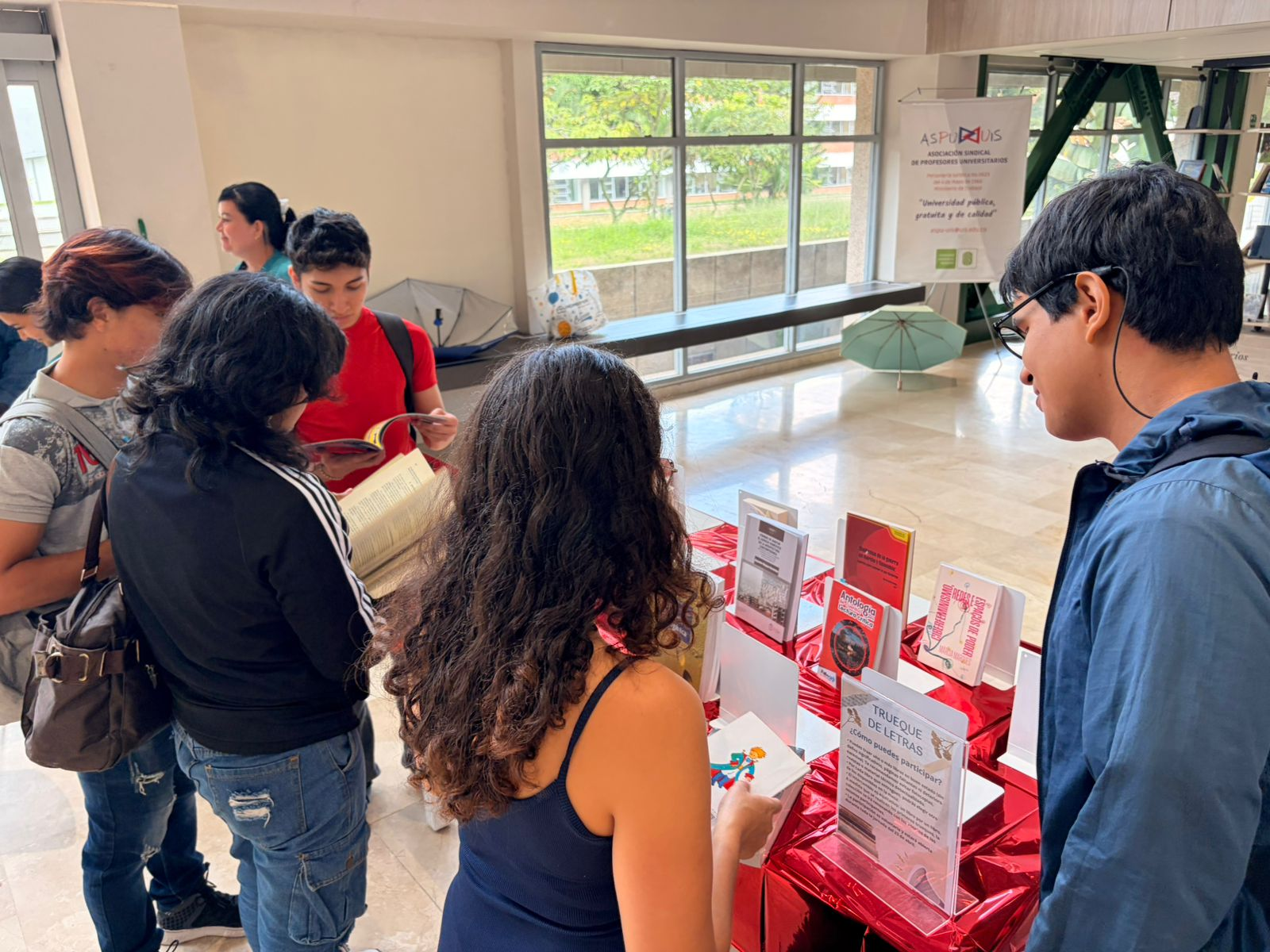 Estudiantes mirando los libros exhibidos en la mesa del trueque